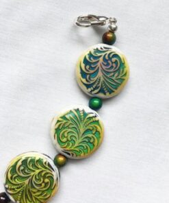 A close up of a necklace with green and yellow designs