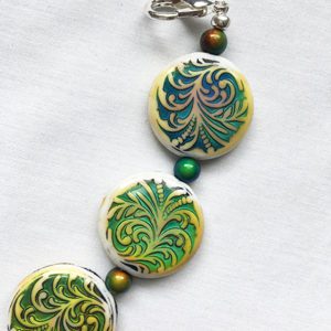 A close up of a necklace with green and yellow designs