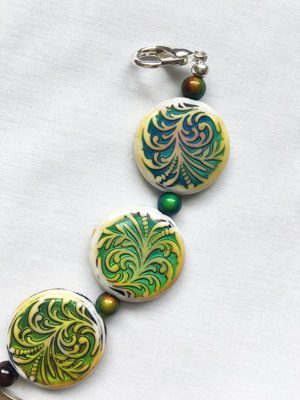 A close up of a necklace with green and yellow designs