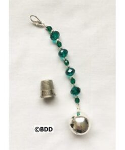 A green bead and bell hanging from the side of a string.