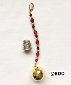A gold bell with red beads hanging from it.
