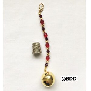 A gold bell with red beads hanging from it.