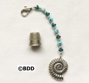 A thimble with a spiral charm and beads.