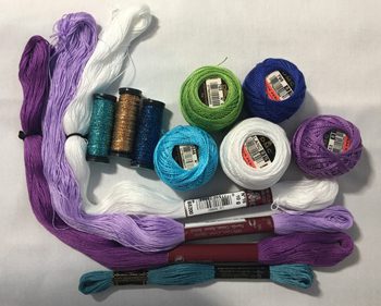 A table with many different types of yarn and sewing needles.