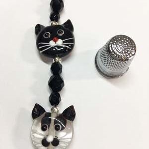 A black and white cat face necklace with a thimble.