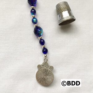 A thimble and a rosary with blue beads.