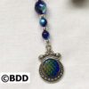 A blue and green bead with a silver pendant.