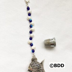 A fish charm with blue beads and white pearls.