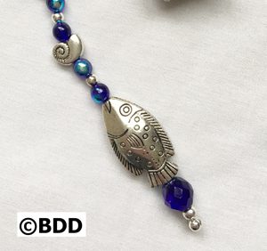 A fish ornament with blue beads and silver accents.