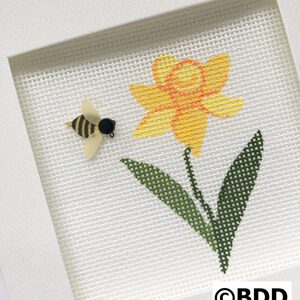 A bee and flower cross stitch pattern in frame.