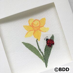 A cross stitch picture of a flower and ladybug.