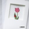 A cross stitch picture of a flower and a ladybug.