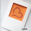 A card with an orange heart stitched on it.