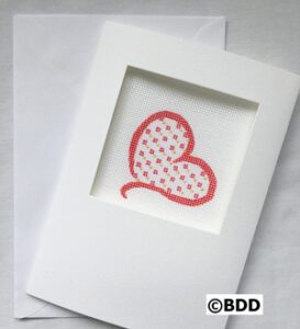 A white card with a red heart in the middle of it.