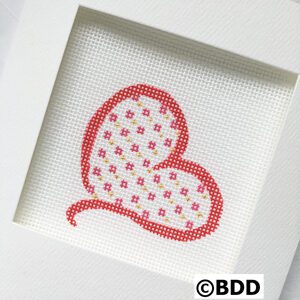 A cross stitch heart in the middle of a frame.