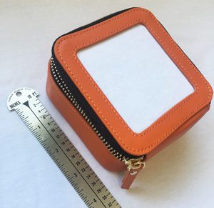 A small orange leather case next to a ruler.