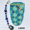 A blue and green cross stitch pattern with a fish charm.