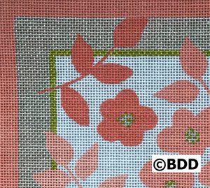 A close up of the flower and leaf pattern on a cross stitch pillow.