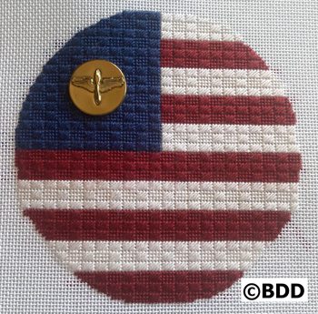 A round american flag with a gold button on it.