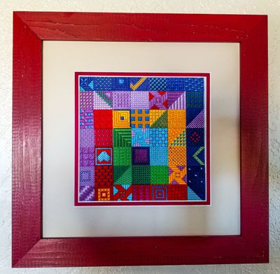 A red frame with a colorful quilt in the middle of it.