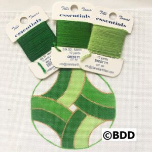 A green circle with three different types of thread.