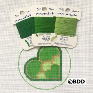 A green heart with three different colors of thread.