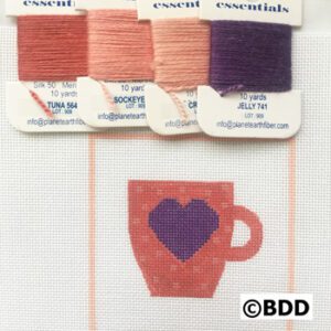 A red cup with purple heart on it and four different colors of thread.