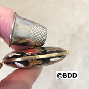 A thimble is being held open to show the inside of it.