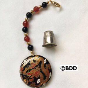 A thimble and bead with a dragon design on it.