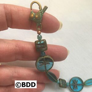 A hand holding a key chain with blue beads.