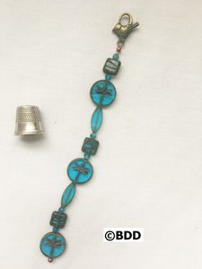 A blue bracelet with some small objects on it