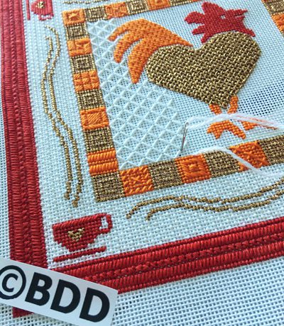 A close up of the embroidery on a red and white rooster.