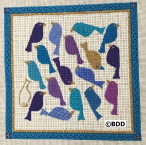 A blue and purple bird pattern on the front of a cross stitch project.