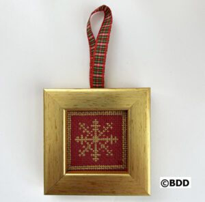 A gold frame with a red and white snowflake ornament hanging on the side.