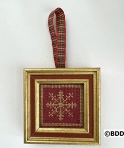 A red and gold framed ornament hanging on a wall.