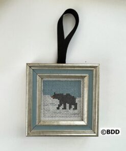 A bear cross stitch ornament hanging on a wall.