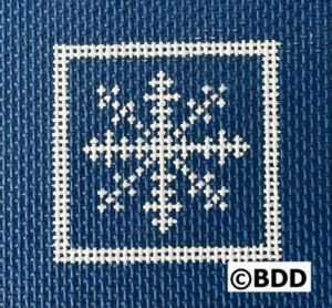 A blue fabric with white cross stitch on it.