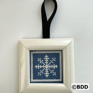 A cross stitch ornament hanging on a black ribbon.