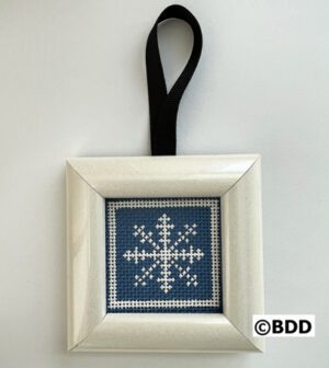 A cross stitch ornament hanging on a black ribbon.