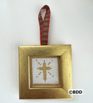 A cross stitched ornament hanging on a gold frame.