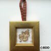 A cross stitch ornament hanging on a gold frame.