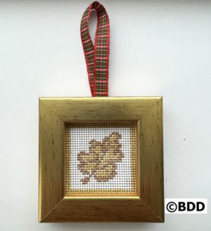 A cross stitch ornament hanging on a gold frame.