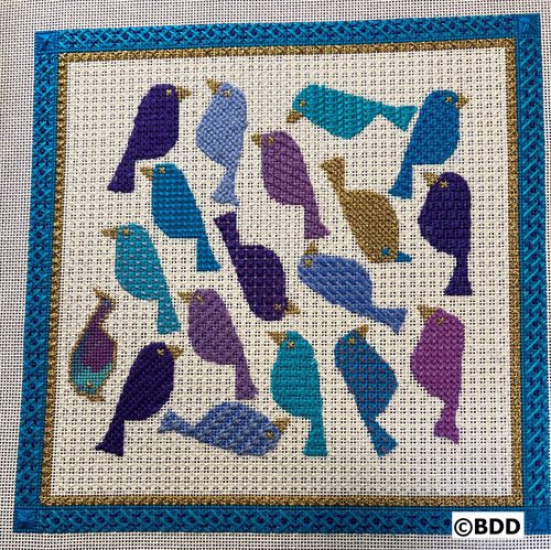 A blue and purple bird pattern on the front of a cross stitch project.