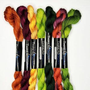 A group of seven skeins of yarn in different colors.