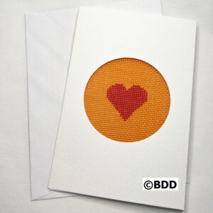 A card with an orange heart stitched on it.