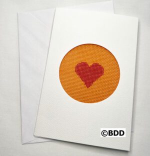 A card with an orange heart stitched on it.