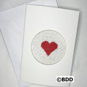 A white card with a red heart stitched on it.