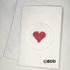 A white card with a red heart stitched on it.