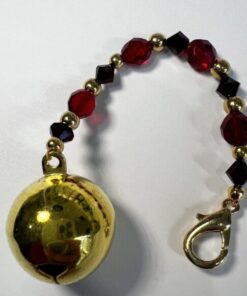 A gold bell with red and black beads on it.