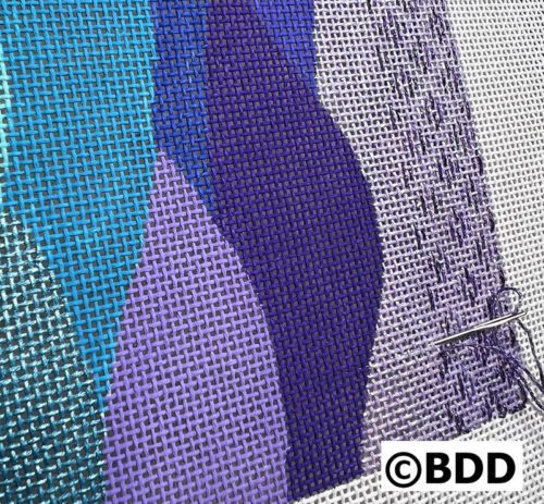 Needlepoint canvas with purple and blue threads.